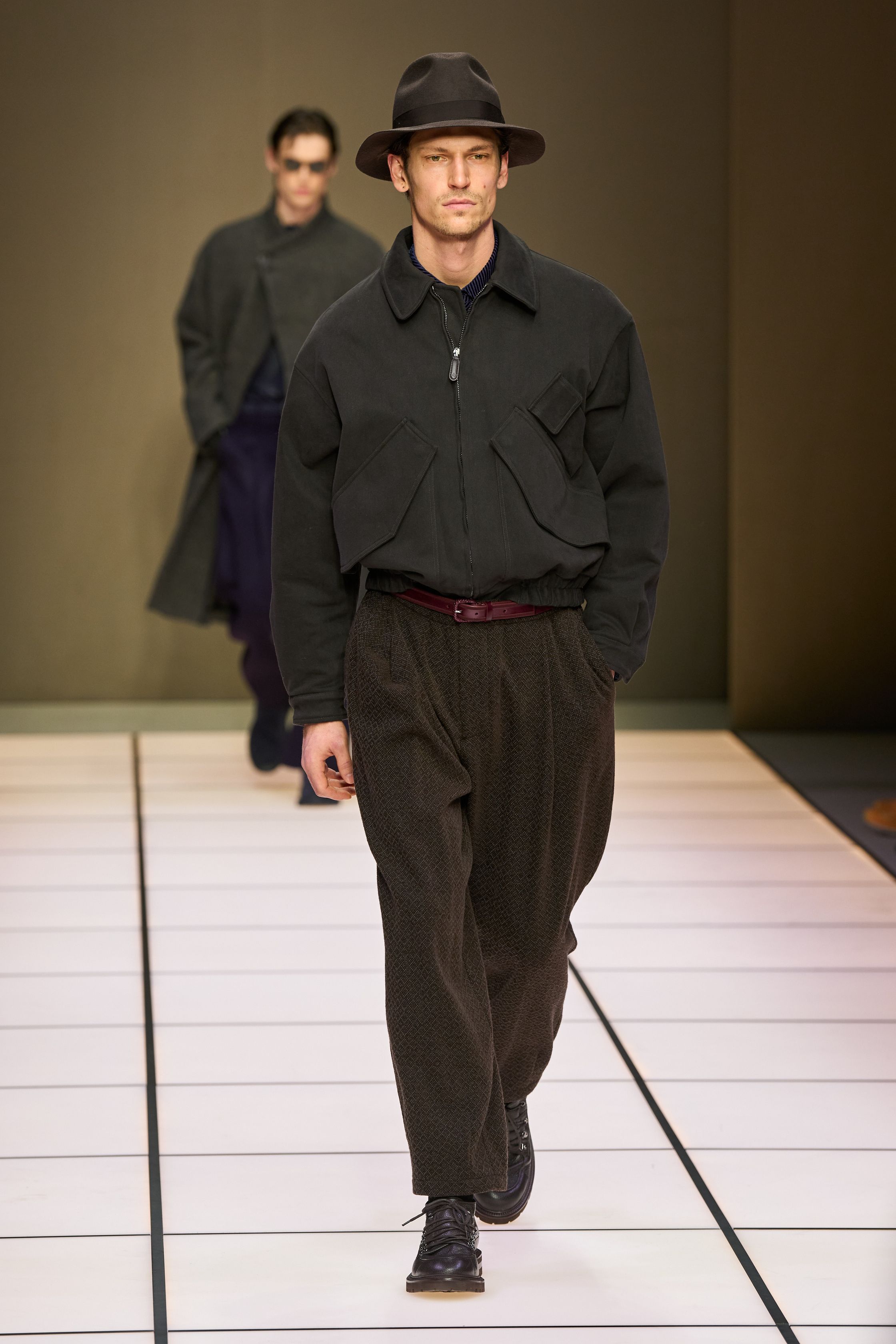 Giorgio Armani 26FW 男装回归品牌最本质的语言：流动、克制与永恒。柔软大衣、宽松长裤、针织与轻结构西装在灰、驼、米与墨绿中缓慢展开，强调身体与面料之间的自然关系。系列几乎不依赖任何戏剧化装饰，却通过比例、步伐与质感建立权威感，是对“真正优雅无需证明”的再次确认，也是一种对快节奏时尚的温和抵抗-顽石频道趋势研究